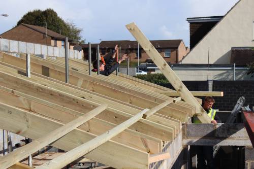Carpenters in action getting one of the roof trusses into place